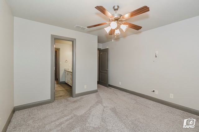 unfurnished bedroom featuring light carpet, baseboards, ensuite bathroom, and ceiling fan