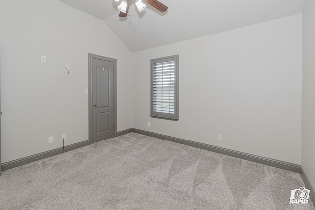 spare room with carpet floors, ceiling fan, vaulted ceiling, and baseboards