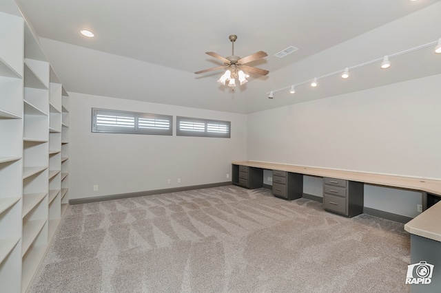 unfurnished office featuring light carpet, a ceiling fan, built in study area, baseboards, and vaulted ceiling