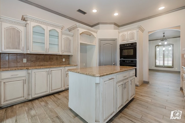 kitchen featuring ornamental molding, arched walkways, decorative backsplash, glass insert cabinets, and light wood-style floors