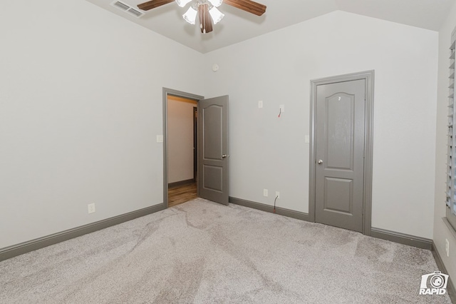 unfurnished bedroom featuring carpet, lofted ceiling, a ceiling fan, and baseboards