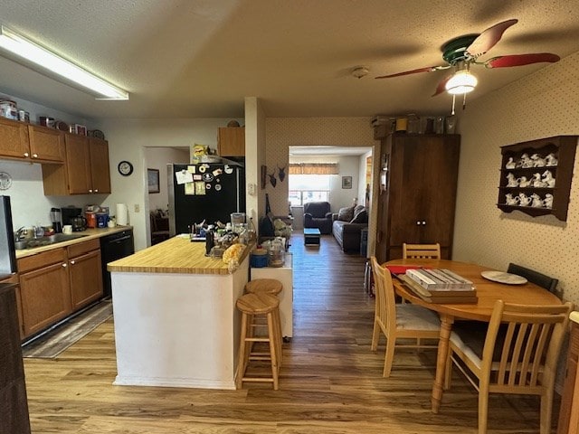 1013 Peachtree Cir, Alpine, TX 79830 - kitchen with freestanding refrigerator, wallpapered walls, black dishwasher, light wood-style floors, and ceiling fan