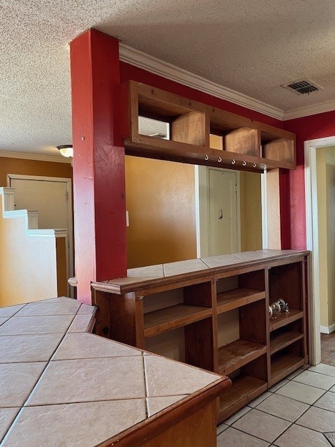 interior space with tile countertops, crown molding, light tile patterned floors, and a textured ceiling