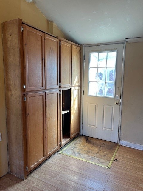 doorway to outside featuring vaulted ceiling and light wood-type flooring