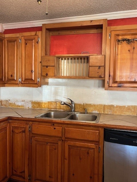 kitchen with tile counters, dishwasher, ornamental molding, and sink