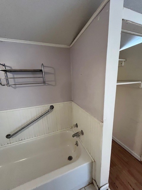 bathroom with a bath, hardwood / wood-style flooring, and crown molding