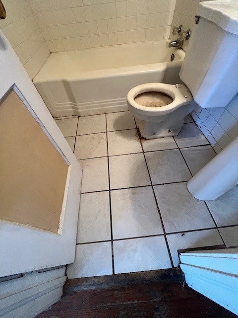 bathroom featuring tile patterned floors, a tub, and toilet