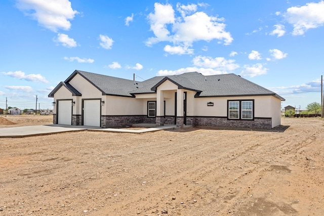view of front of home featuring stucco siding, stone siding, an attached garage, and driveway