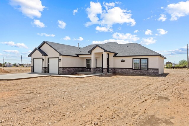12645 W Maria Dr, Odessa, TX 79764 - view of front of home featuring stucco siding, stone siding, an attached garage, and driveway