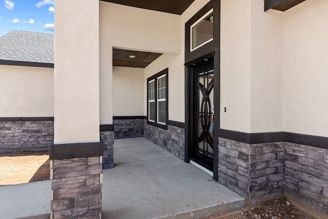 property entrance featuring stone siding and stucco siding