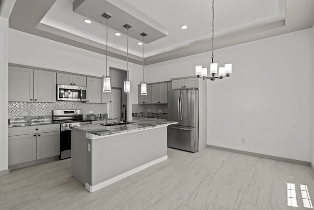 kitchen with appliances with stainless steel finishes, gray cabinetry, a sink, a tray ceiling, and recessed lighting