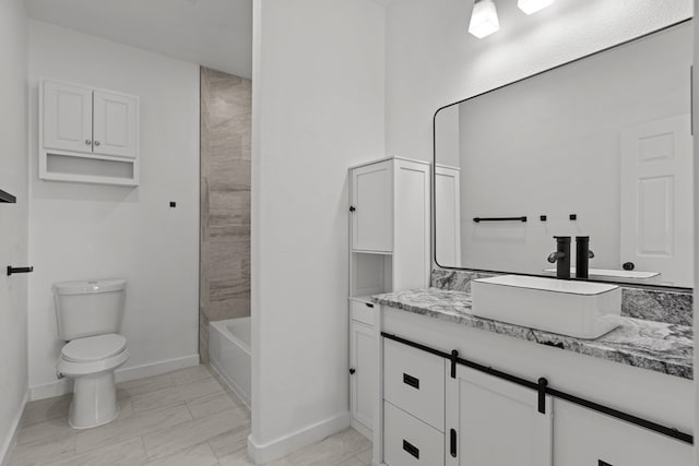 bathroom with baseboards, toilet, vanity, and  shower combination