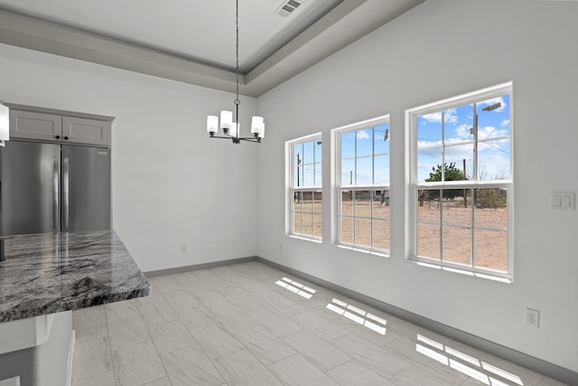 unfurnished dining area with a chandelier and baseboards