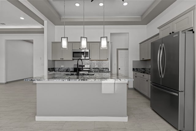 kitchen featuring stainless steel appliances, gray cabinets, light stone countertops, and decorative backsplash