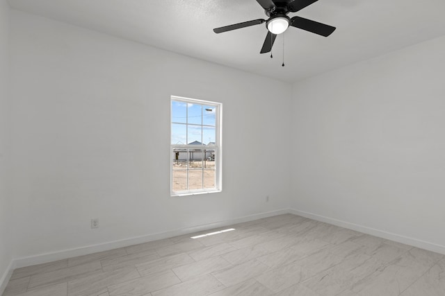 spare room with baseboards and ceiling fan