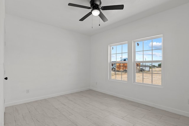 spare room featuring ceiling fan and baseboards