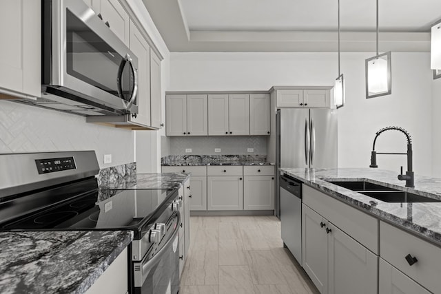 kitchen featuring stainless steel appliances, a sink, tasteful backsplash, dark stone counters, and light marble finish flooring