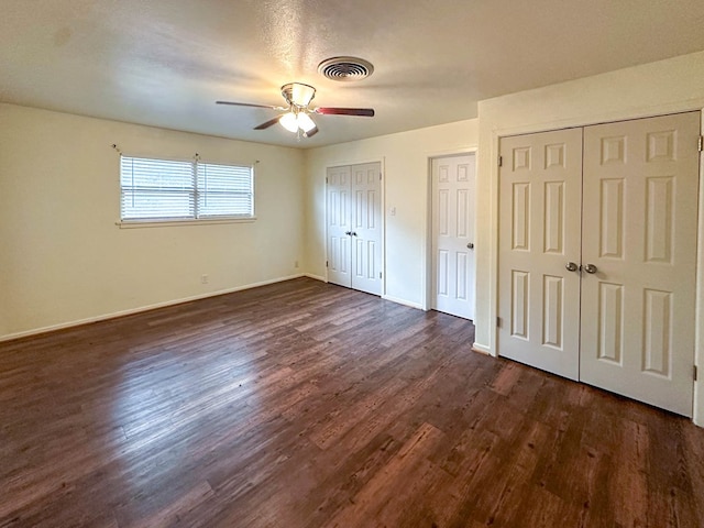 111 N 24th St, Lamesa, TX 79331 - unfurnished bedroom featuring two closets, dark wood finished floors, baseboards, and a ceiling fan