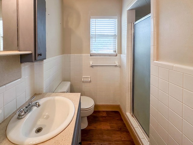 111 N 24th St, Lamesa, TX 79331 - bathroom featuring tile walls, a wainscoted wall, a stall shower, wood finished floors, and toilet