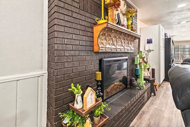 811 NW 7th St, Andrews, TX 79714 - detailed view of a brick fireplace, wood finished floors, wainscoting, a decorative wall, and a textured ceiling