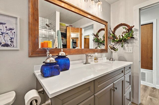 811 NW 7th St, Andrews, TX 79714 - bathroom with vanity, toilet, wood finished floors, and a tile shower