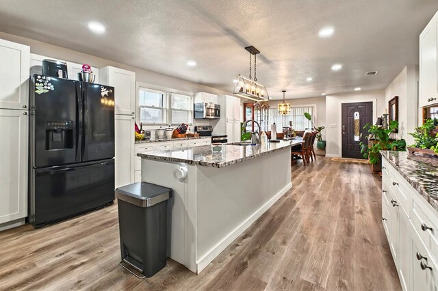 811 NW 7th St, Andrews, TX 79714 - kitchen featuring stainless steel appliances, a sink, an island with sink, light wood-type flooring, and recessed lighting