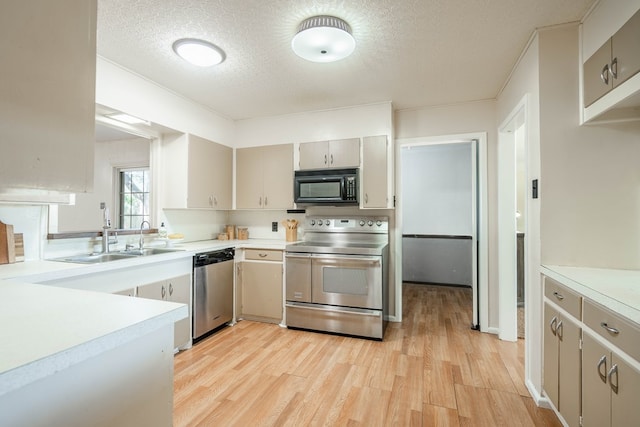 1403 E 17th St, Odessa, TX 79761 - kitchen featuring stainless steel appliances, a sink, light countertops, light wood-style floors, and a textured ceiling