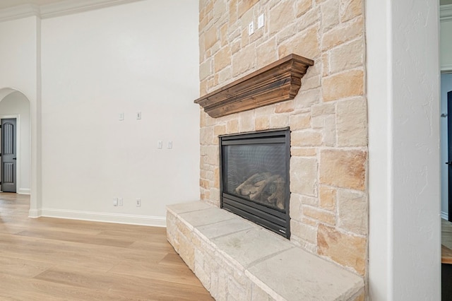 details featuring hardwood / wood-style floors, a stone fireplace, and crown molding