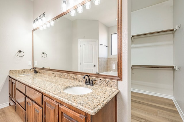 bathroom with a bath, hardwood / wood-style floors, and vanity