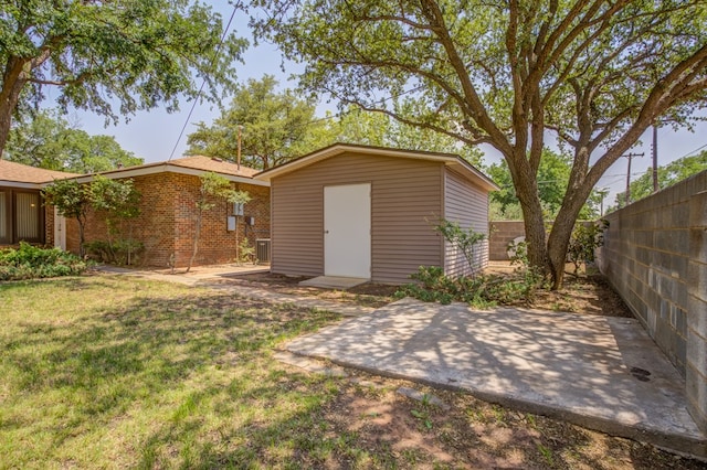 rear view of property featuring a storage shed, an outbuilding, a lawn, a fenced backyard, and a patio area