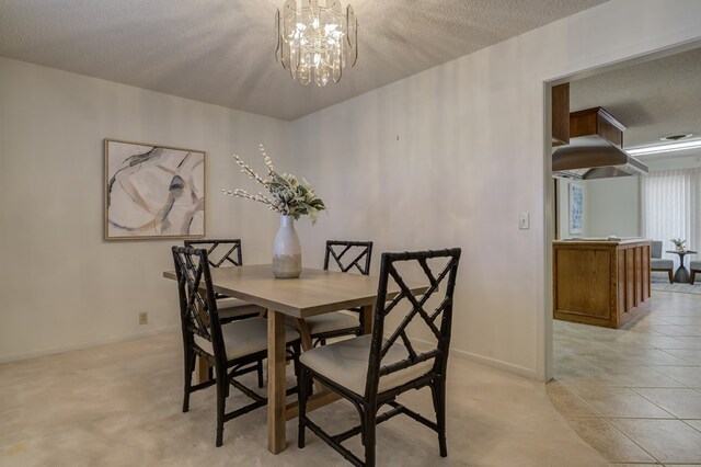 dining area featuring a textured ceiling, baseboards, and a notable chandelier