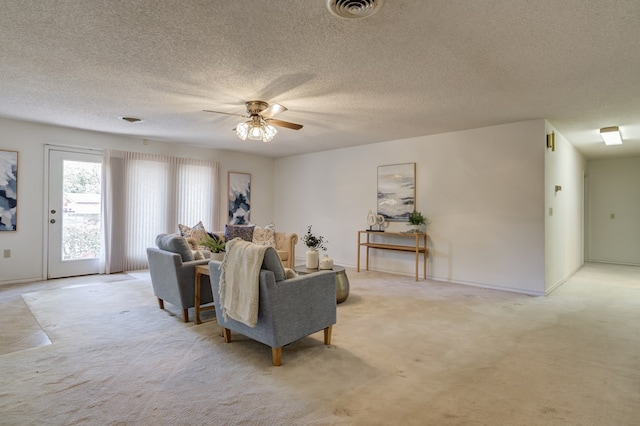 living room featuring light carpet, visible vents, ceiling fan, and a textured ceiling
