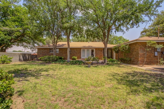 rear view of house featuring brick siding, a yard, and fence