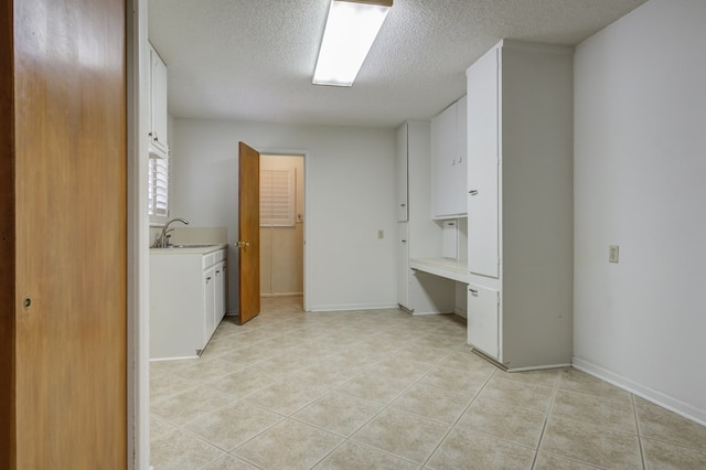 laundry room with a sink, a textured ceiling, and light tile patterned floors