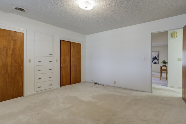 unfurnished bedroom with a textured ceiling, a closet, visible vents, and carpet floors