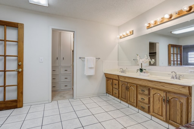 full bath featuring a sink, double vanity, a textured ceiling, and tile patterned floors