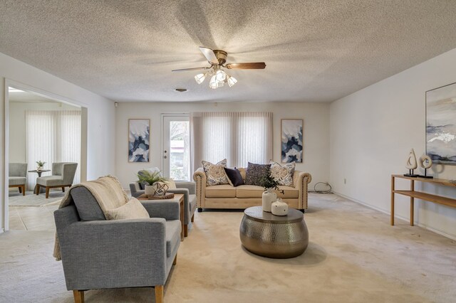 living area featuring a ceiling fan, light carpet, and a textured ceiling