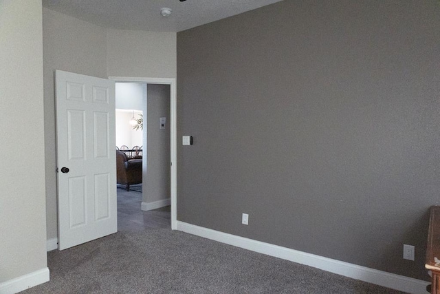 unfurnished room with dark carpet