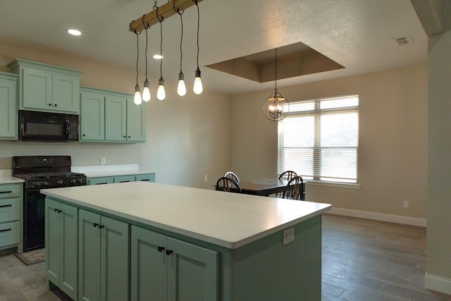 kitchen with a center island, black appliances, a raised ceiling, and green cabinetry