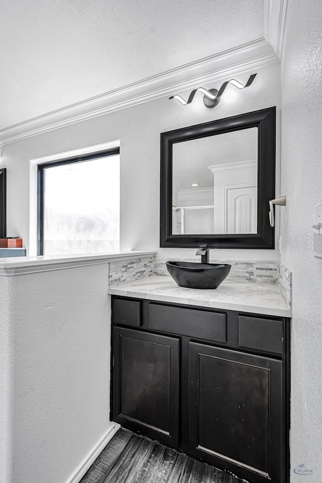 bathroom featuring crown molding, vanity, a textured wall, and wood finished floors