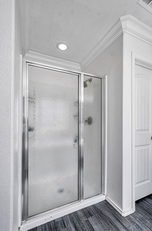 bathroom with ornamental molding, a stall shower, wood finished floors, a textured ceiling, and baseboards