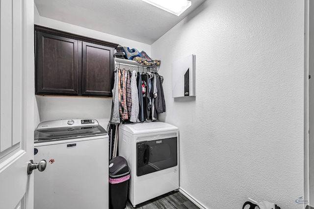 laundry room with washing machine and dryer, cabinet space, a textured wall, and baseboards