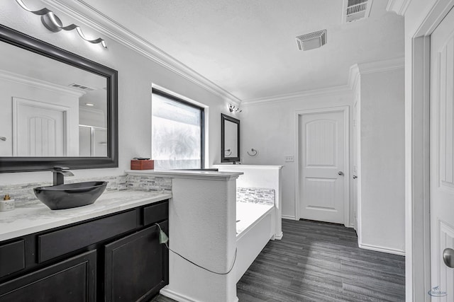 full bath with crown molding, wood finished floors, a tub to relax in, and vanity