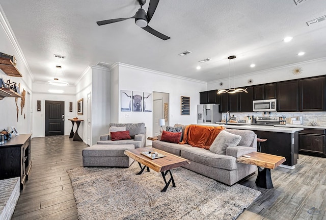 living area featuring light wood-type flooring, ceiling fan, crown molding, a textured ceiling, and recessed lighting