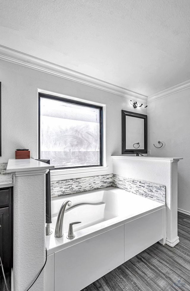 bathroom with crown molding, wood finished floors, vanity, a bath, and a textured ceiling