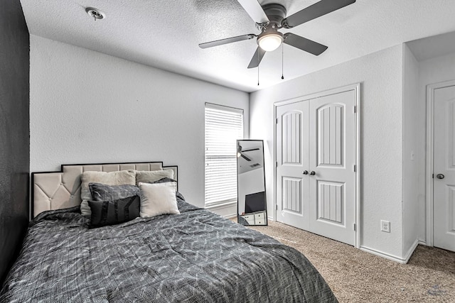 carpeted bedroom featuring a textured wall, a closet, ceiling fan, and a textured ceiling