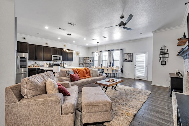 living area featuring ceiling fan, a fireplace, crown molding, baseboards, and dark wood-style flooring