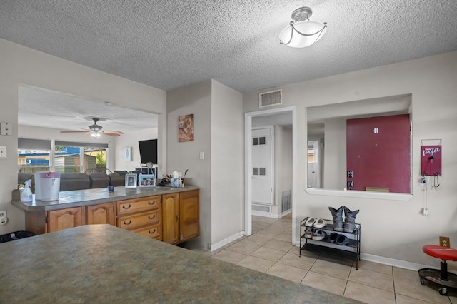 2110 Redbud Ave, Odessa, TX 79761 - kitchen with light tile patterned floors, a ceiling fan, a textured ceiling, baseboards, and brown cabinetry
