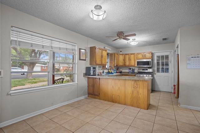 2110 Redbud Ave, Odessa, TX 79761 - kitchen featuring stainless steel appliances, a peninsula, ceiling fan, light tile patterned flooring, and baseboards