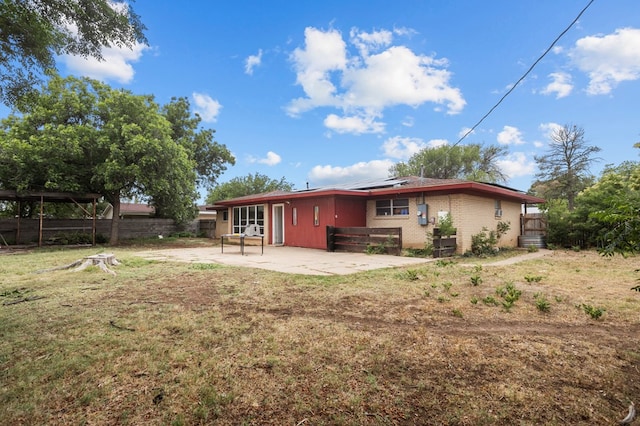 2110 Redbud Ave, Odessa, TX 79761 - rear view of property featuring roof mounted solar panels, brick siding, and a patio